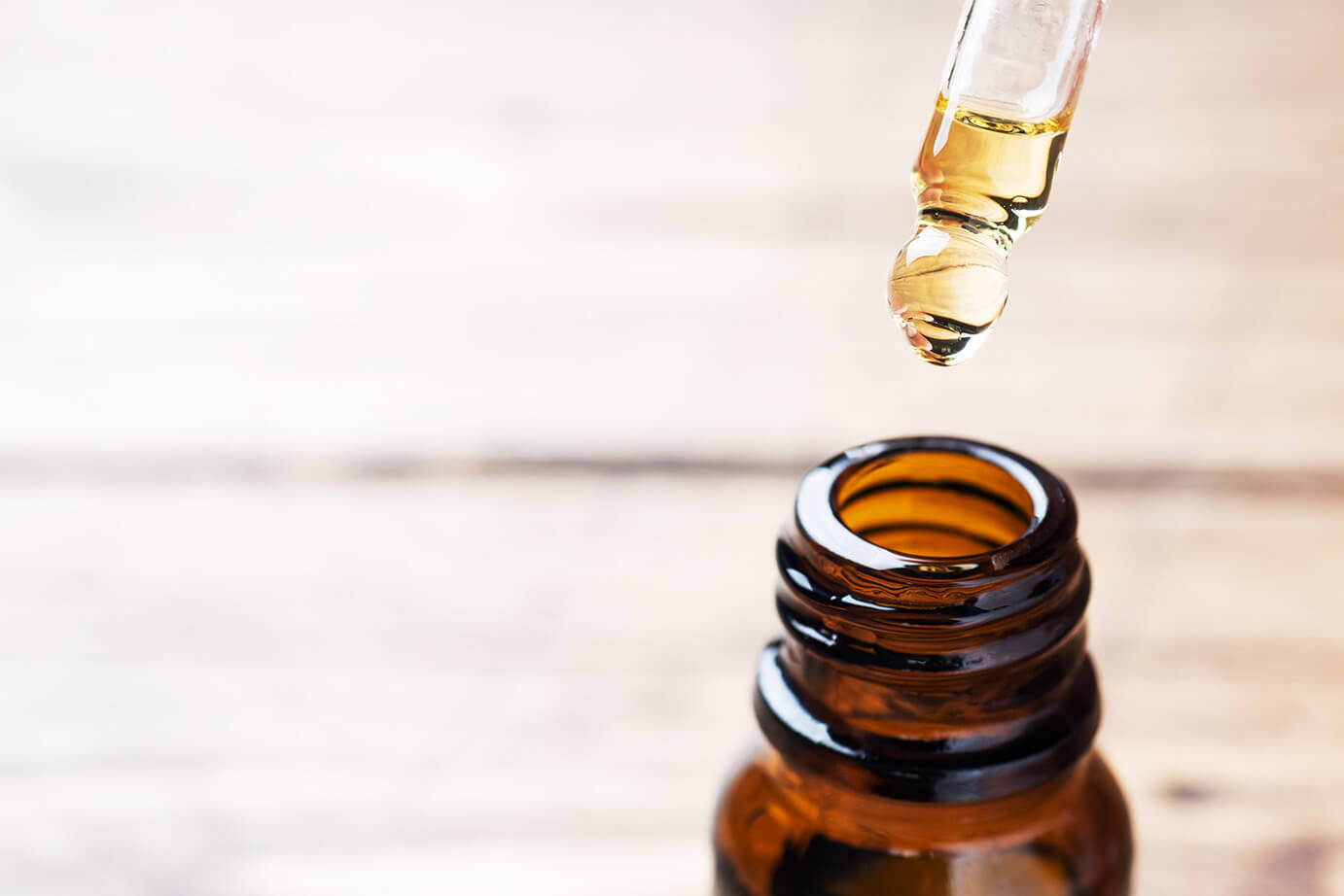 A brown glass bottle containing essential oils on a bright wodden floor