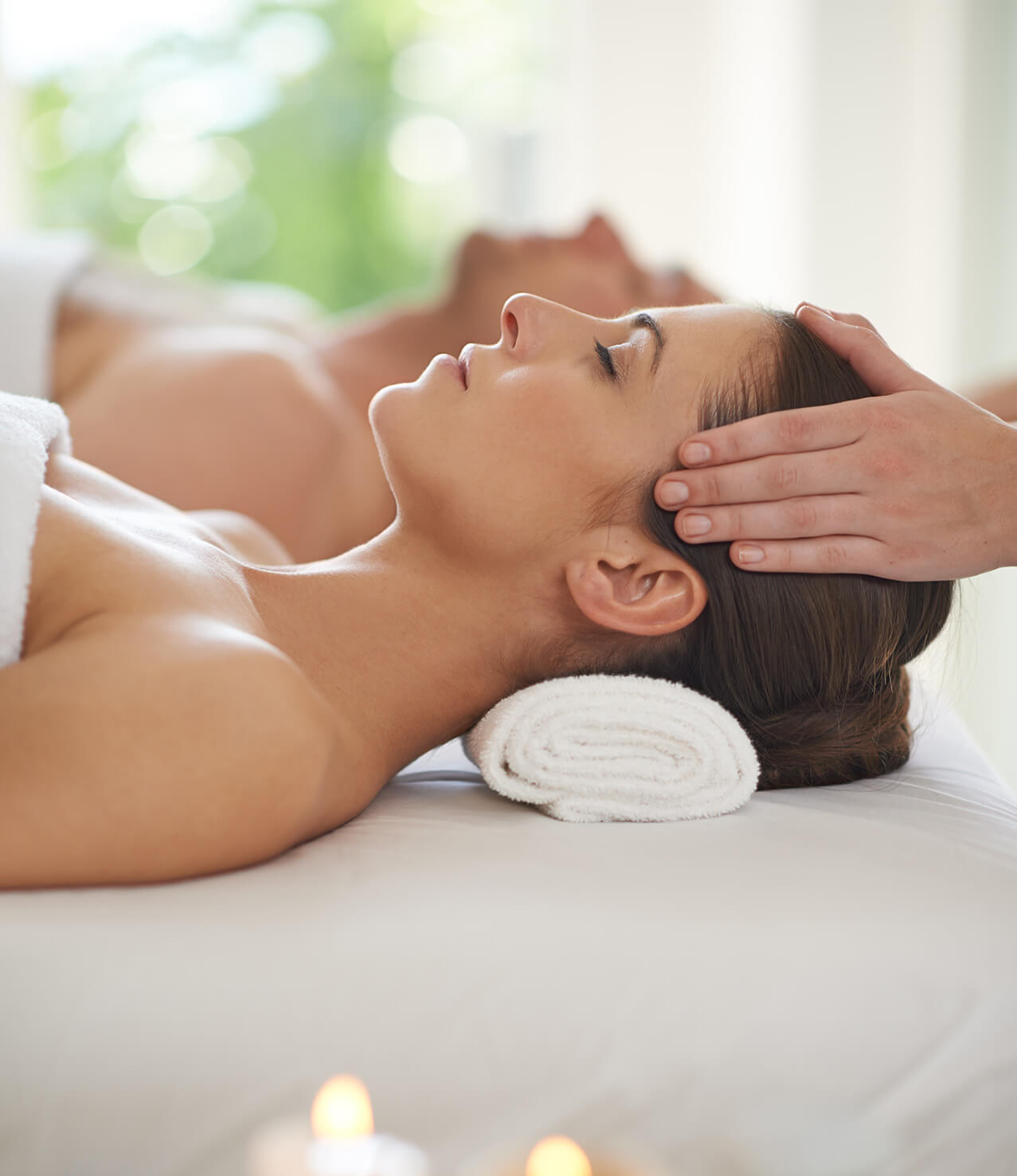 Side view of a woman having a head massage with her head on a towel