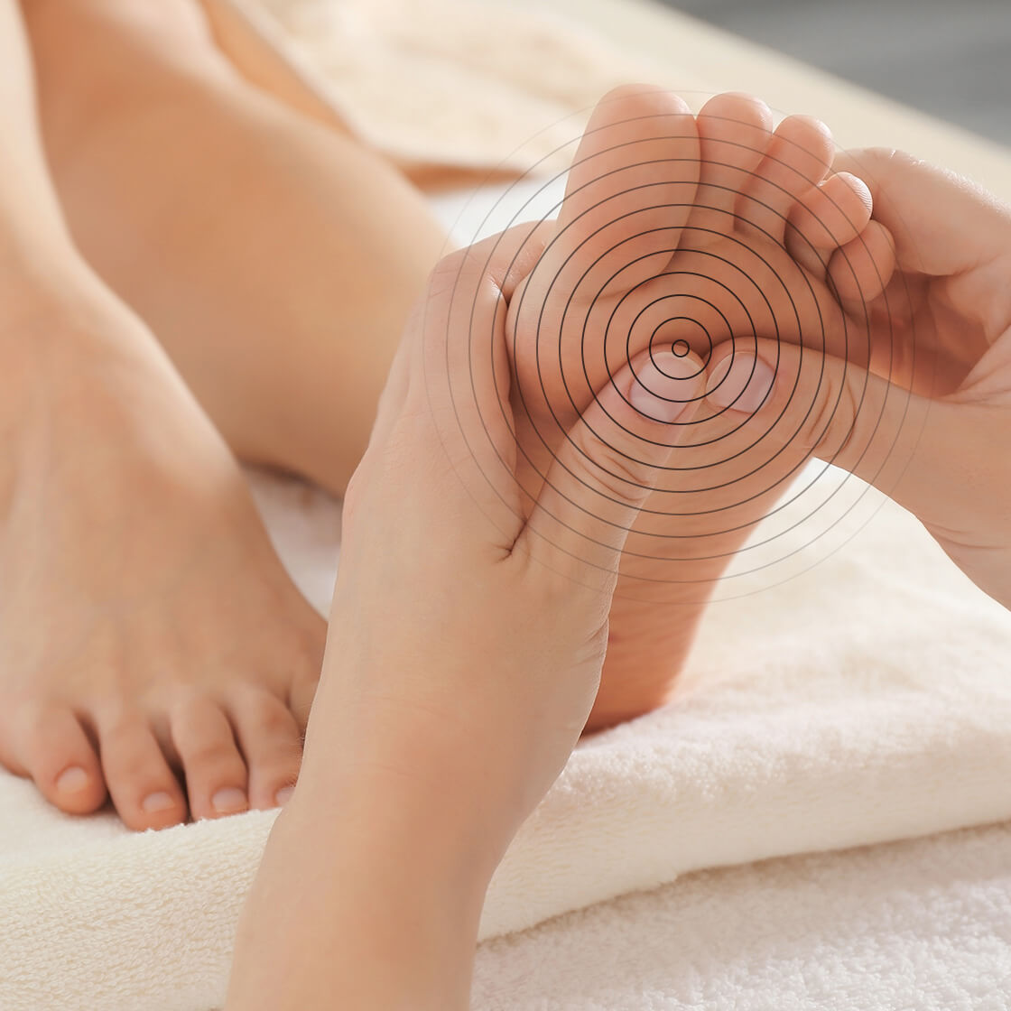 A hand applying pressure to a patients feet using their thumbs