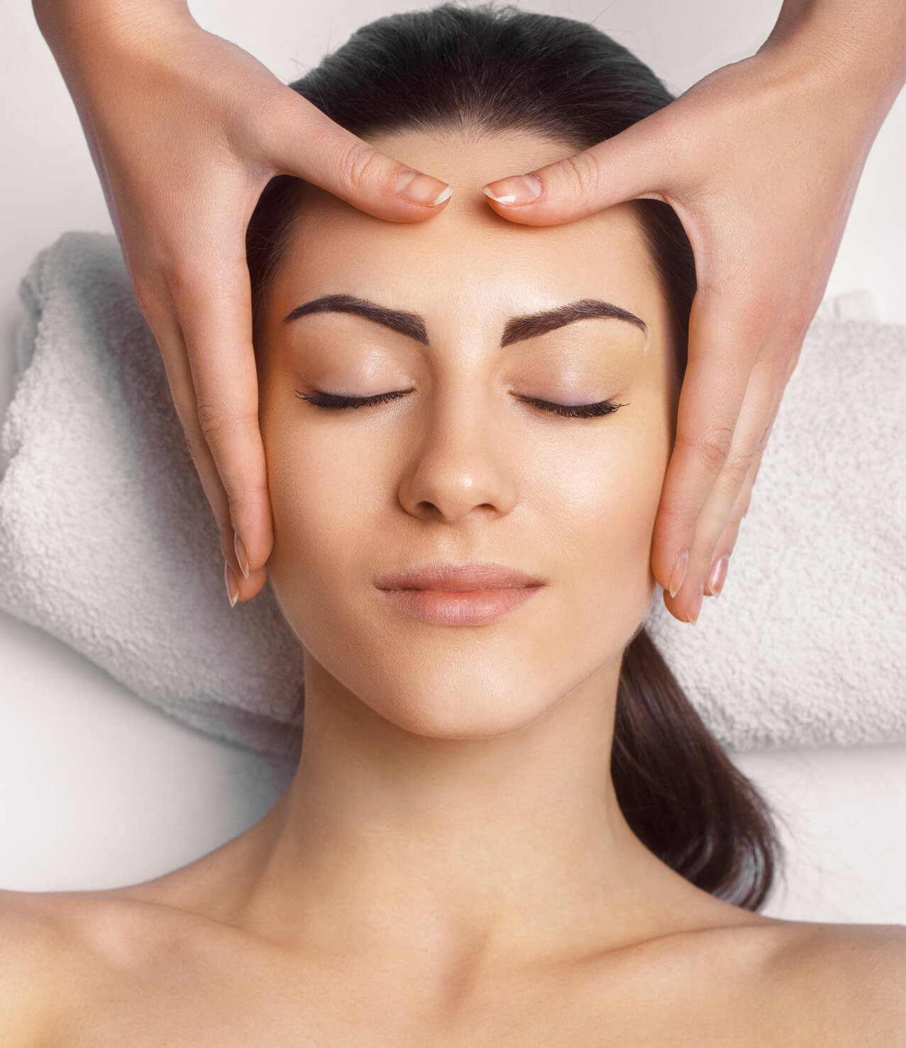 Side view of a woman having a head massage with her head on a towel